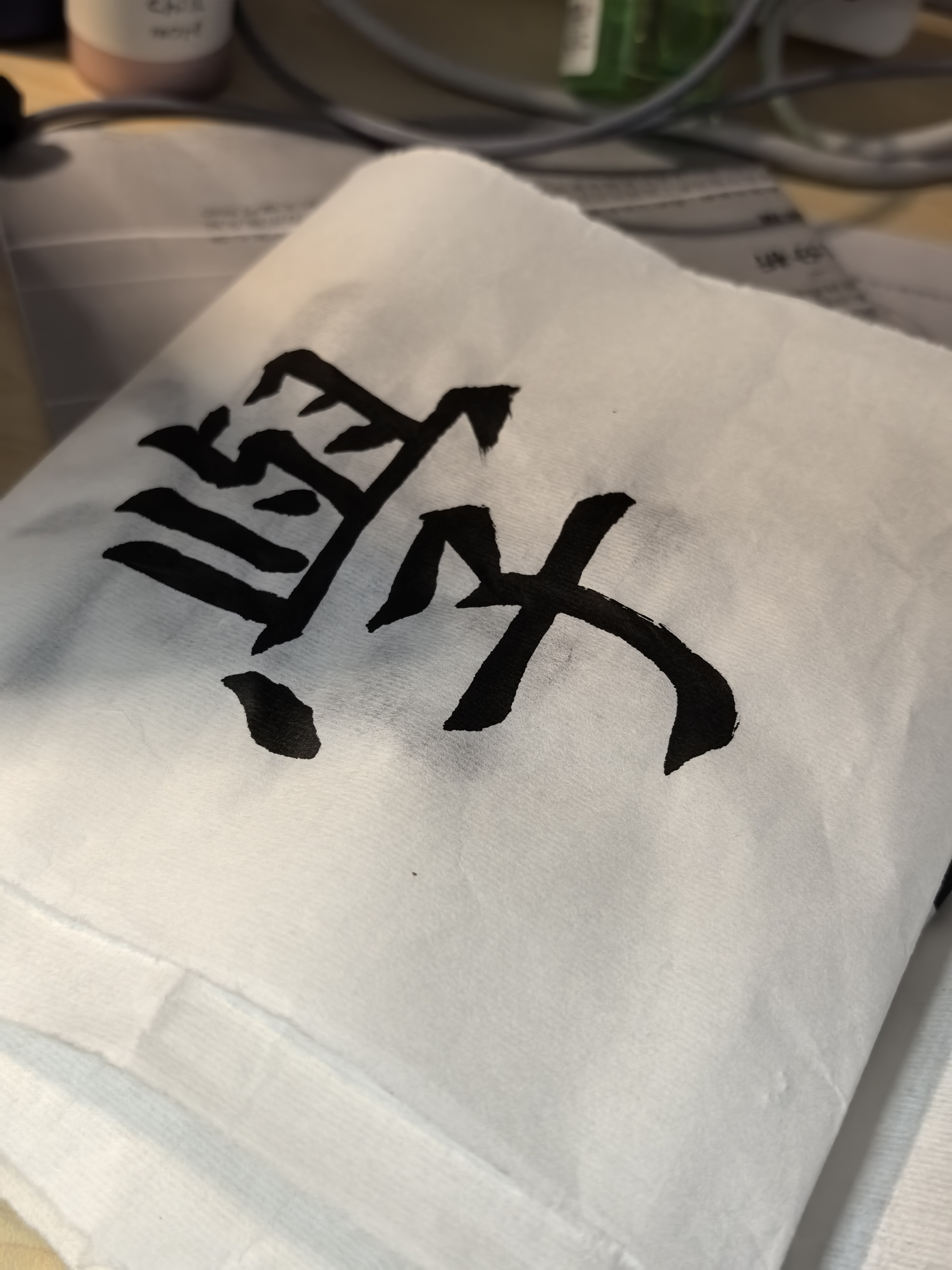 The photo shows a white cloth with a black kanji character painted in calligraphy on it. (Captioned by AI)