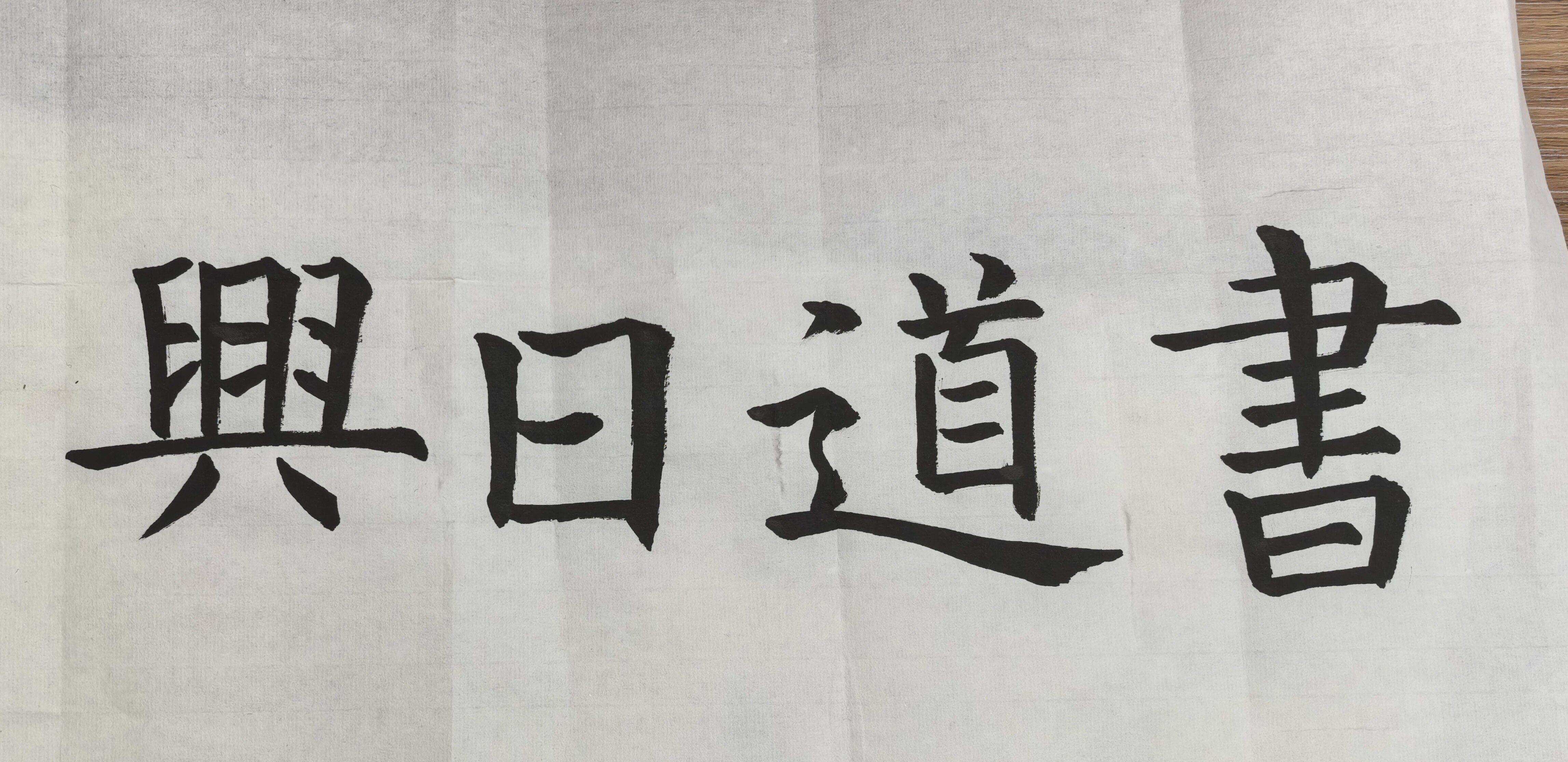 The image shows a piece of paper with four Japanese characters written on it with black ink. (Captioned by AI)