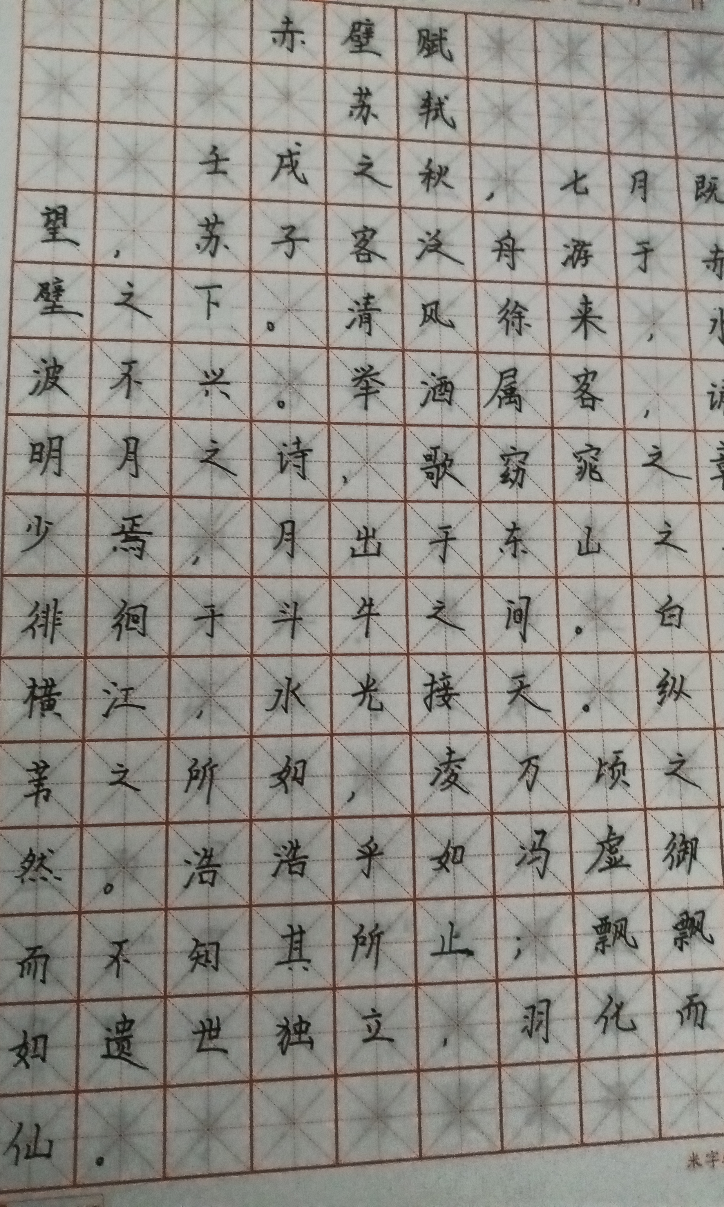 A sheet of paper features Chinese calligraphy practice with characters neatly written within a gridded framework. (Captioned by AI)