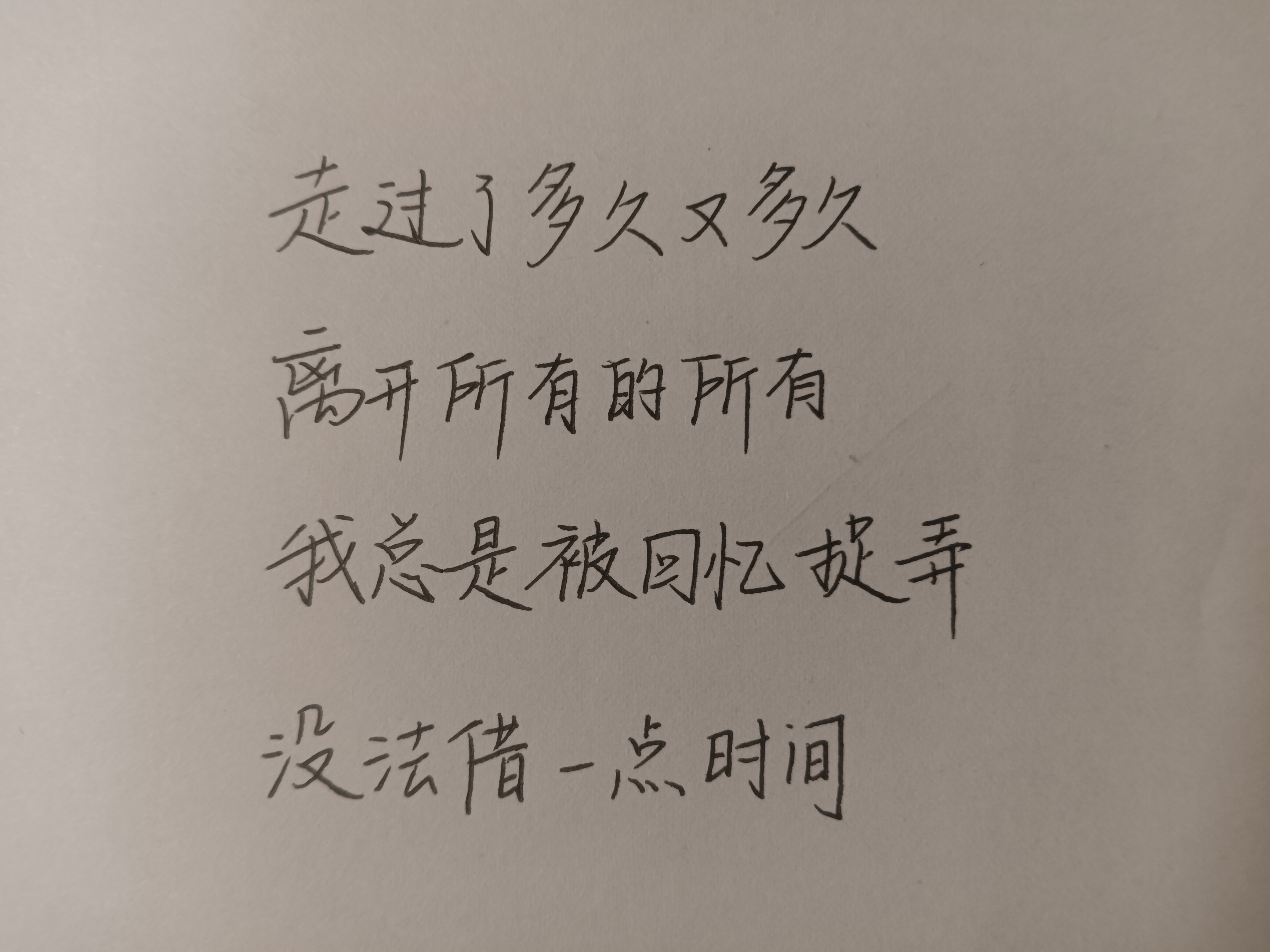 The image shows a piece of paper with handwritten Chinese characters, possibly a poem or a philosophical quote. (Captioned by AI)