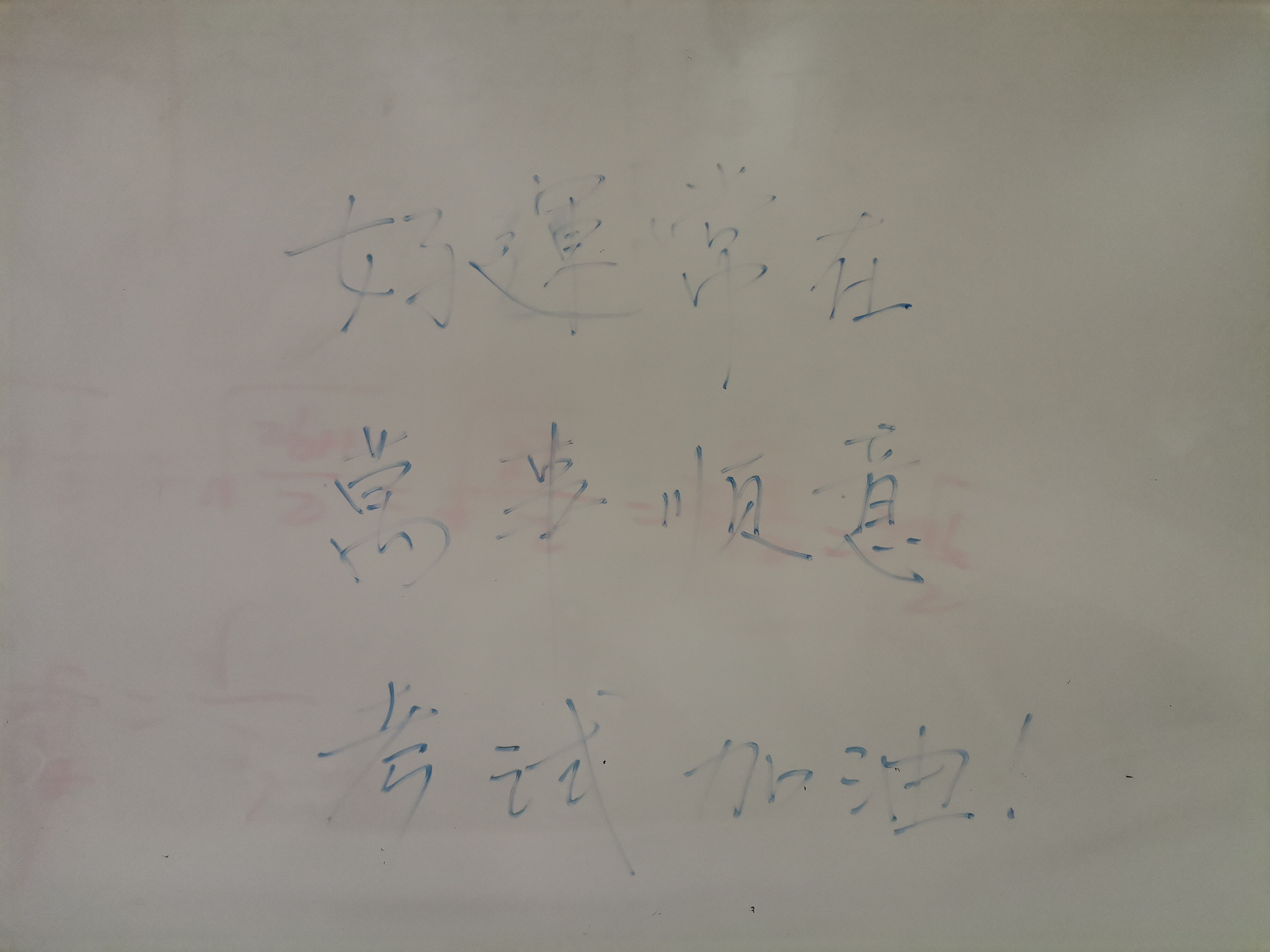 A whiteboard displays three lines of handwritten Chinese text. (Captioned by AI)